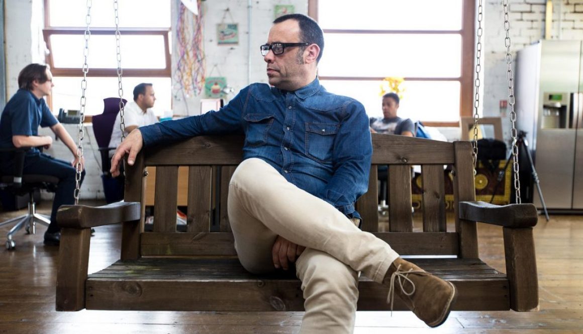 Homem sentado em cadeira de balanço em momento de descompressão em espaço coworking